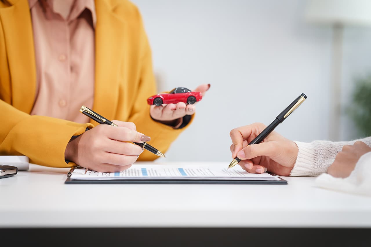 車の模型を持っている女性が書類を記載している様子